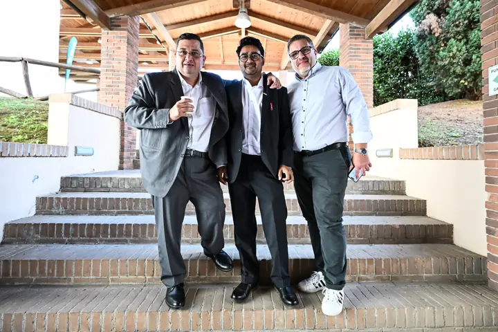 Three event attendees standing together on outdoor brick steps in Rome