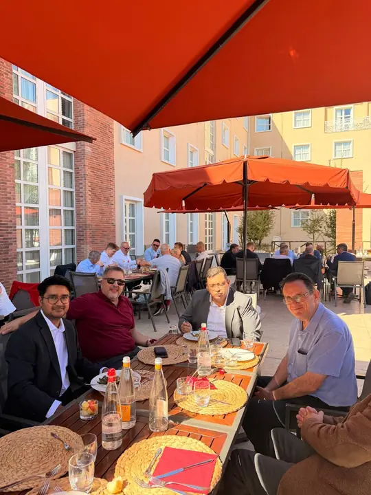 Distributors sharing lunch at an outdoor terrace under red umbrellas